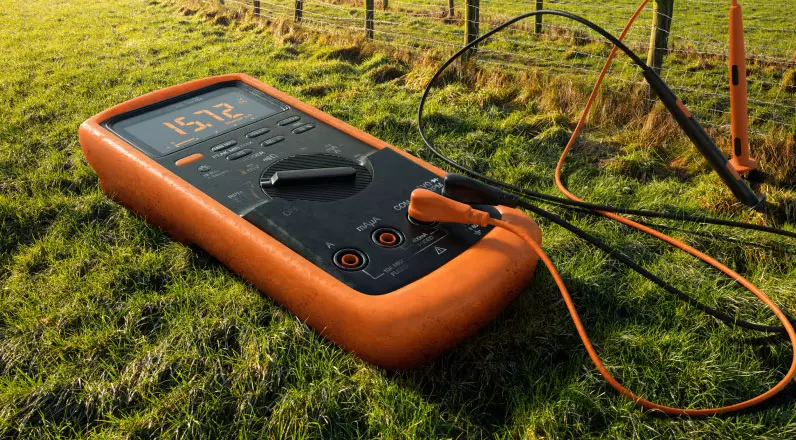 alt="Close-up of an electrical measuring device on grass."