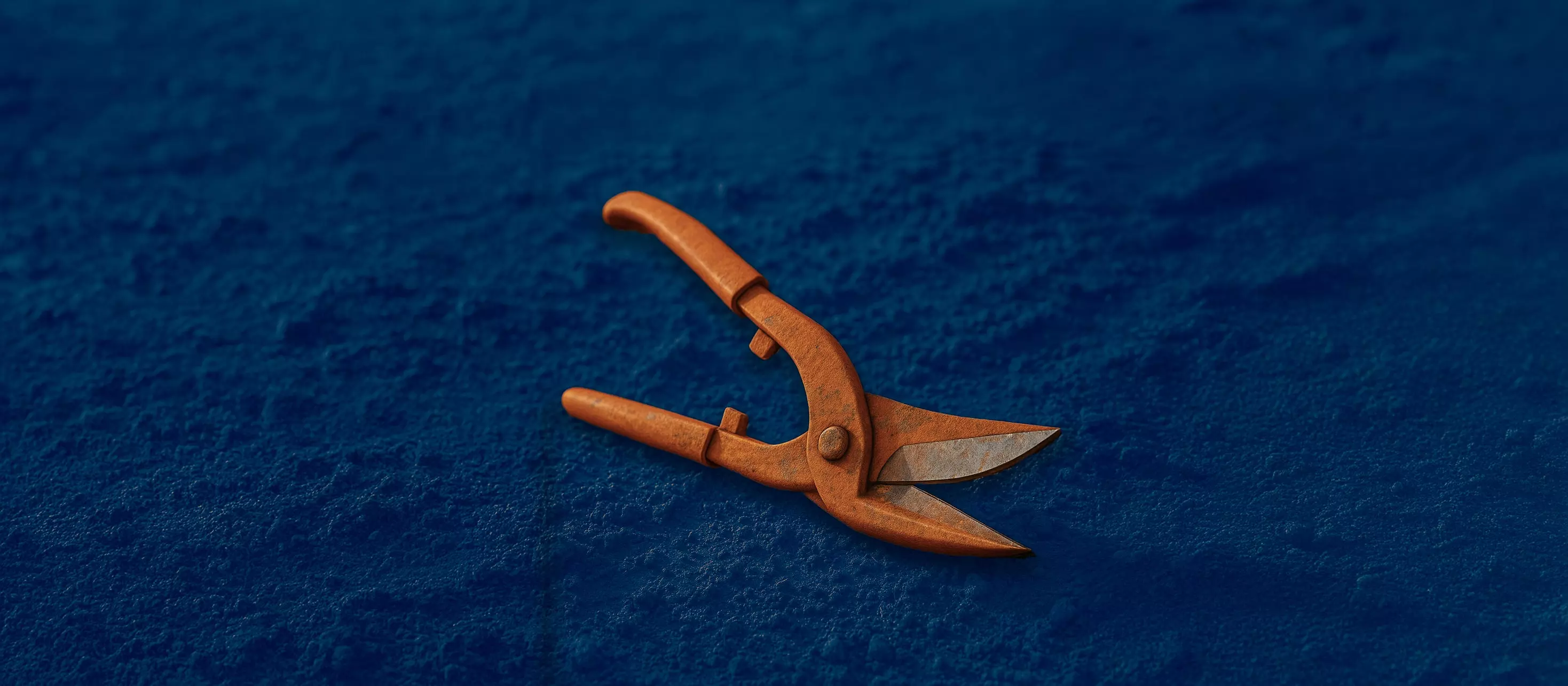 Large orange  industrial shears lying on the ground.