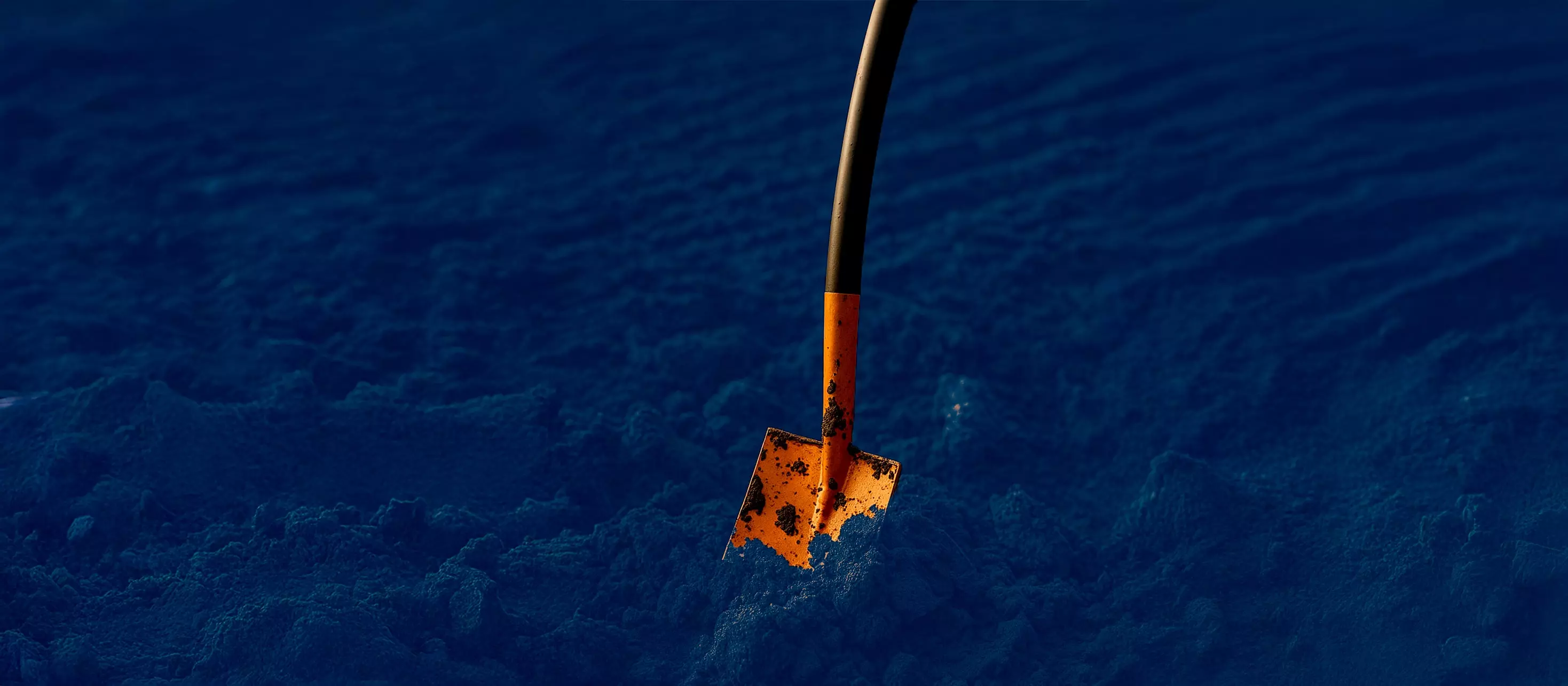 Orange shovel stuck in soil, representing infra work.