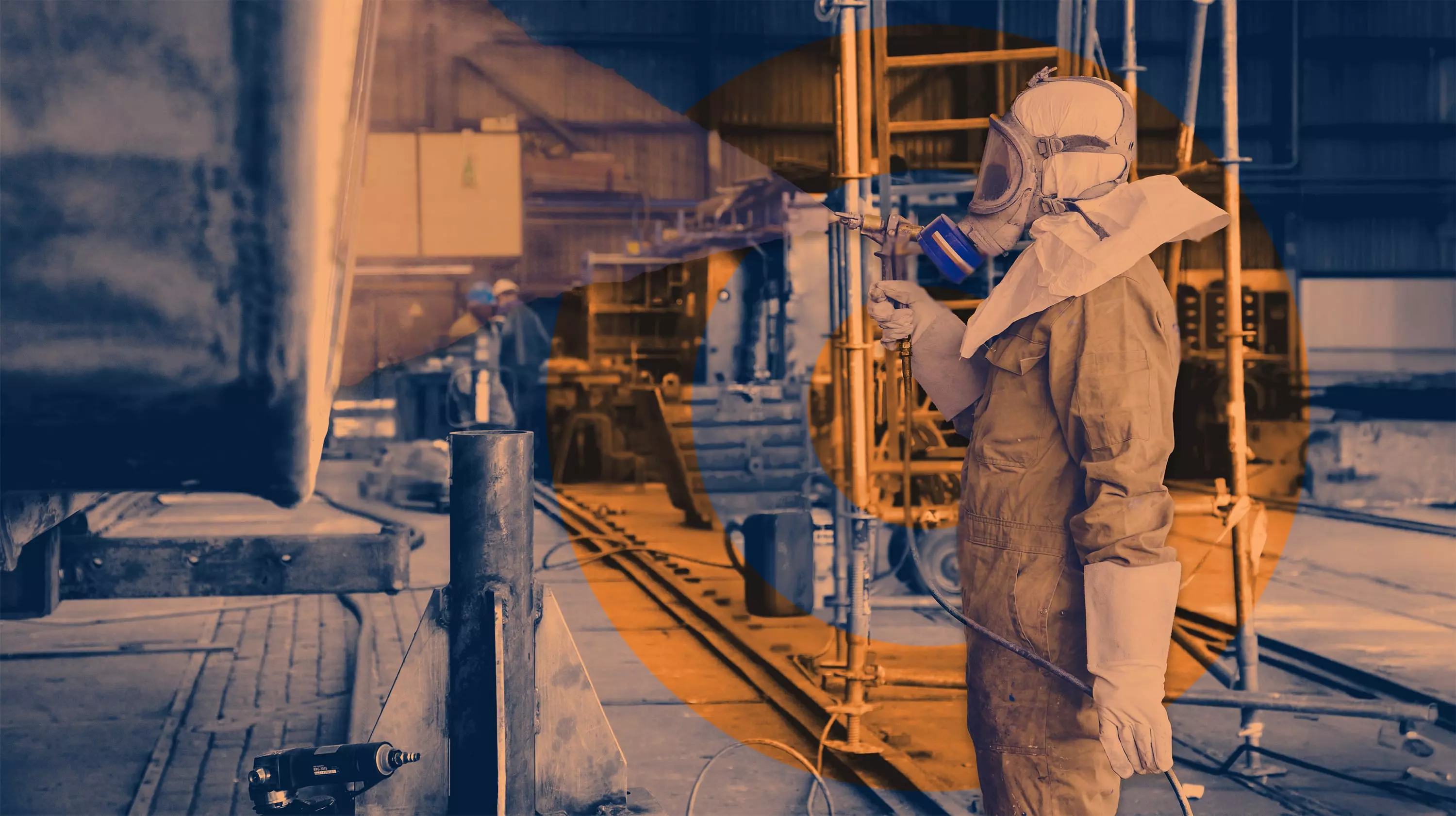 Industrial worker in full protective gear using a spray gun inside a factory or workshop setting.