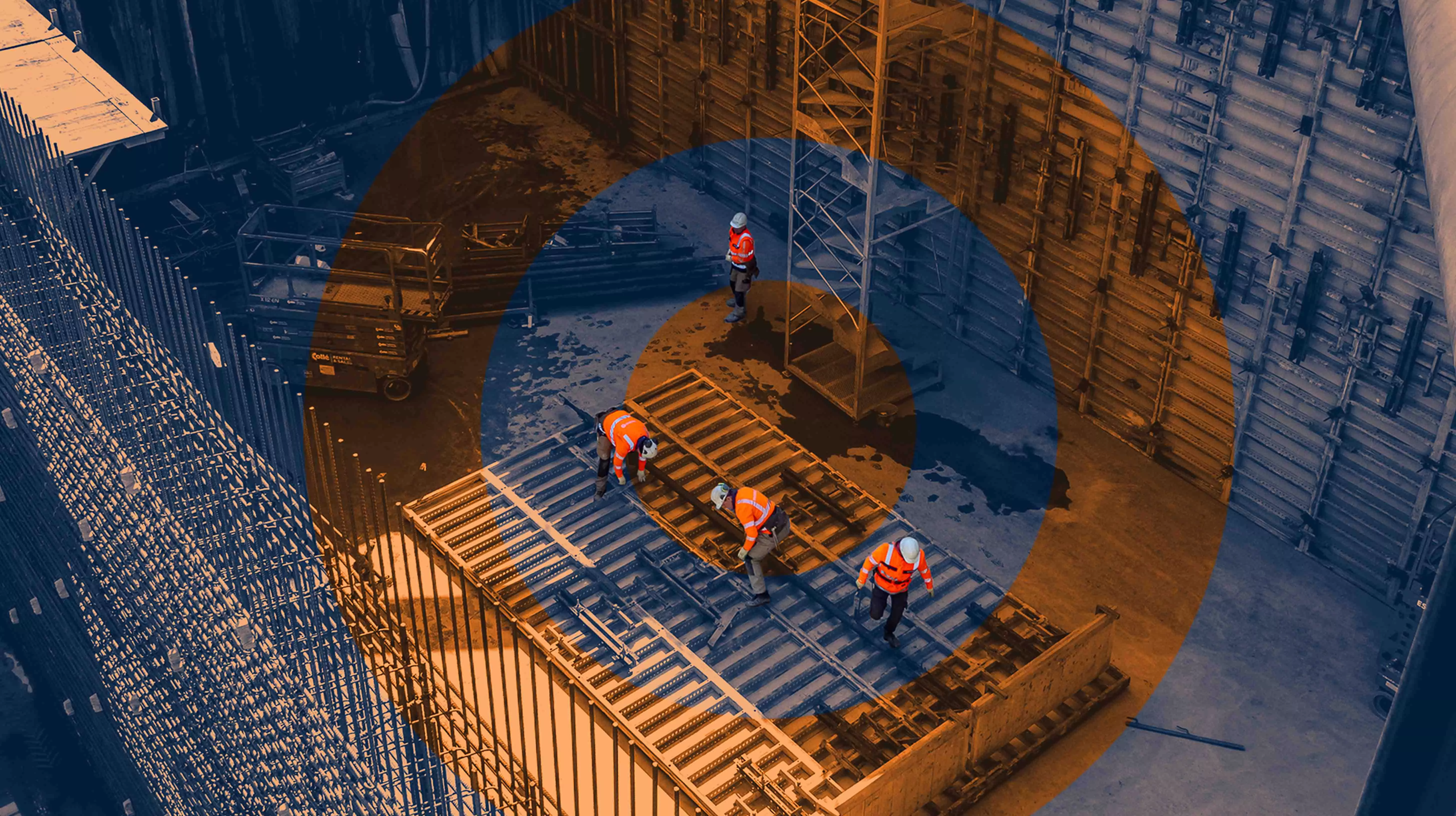 Overhead view of construction workers assembling a large structural frame inside a deep excavation site.