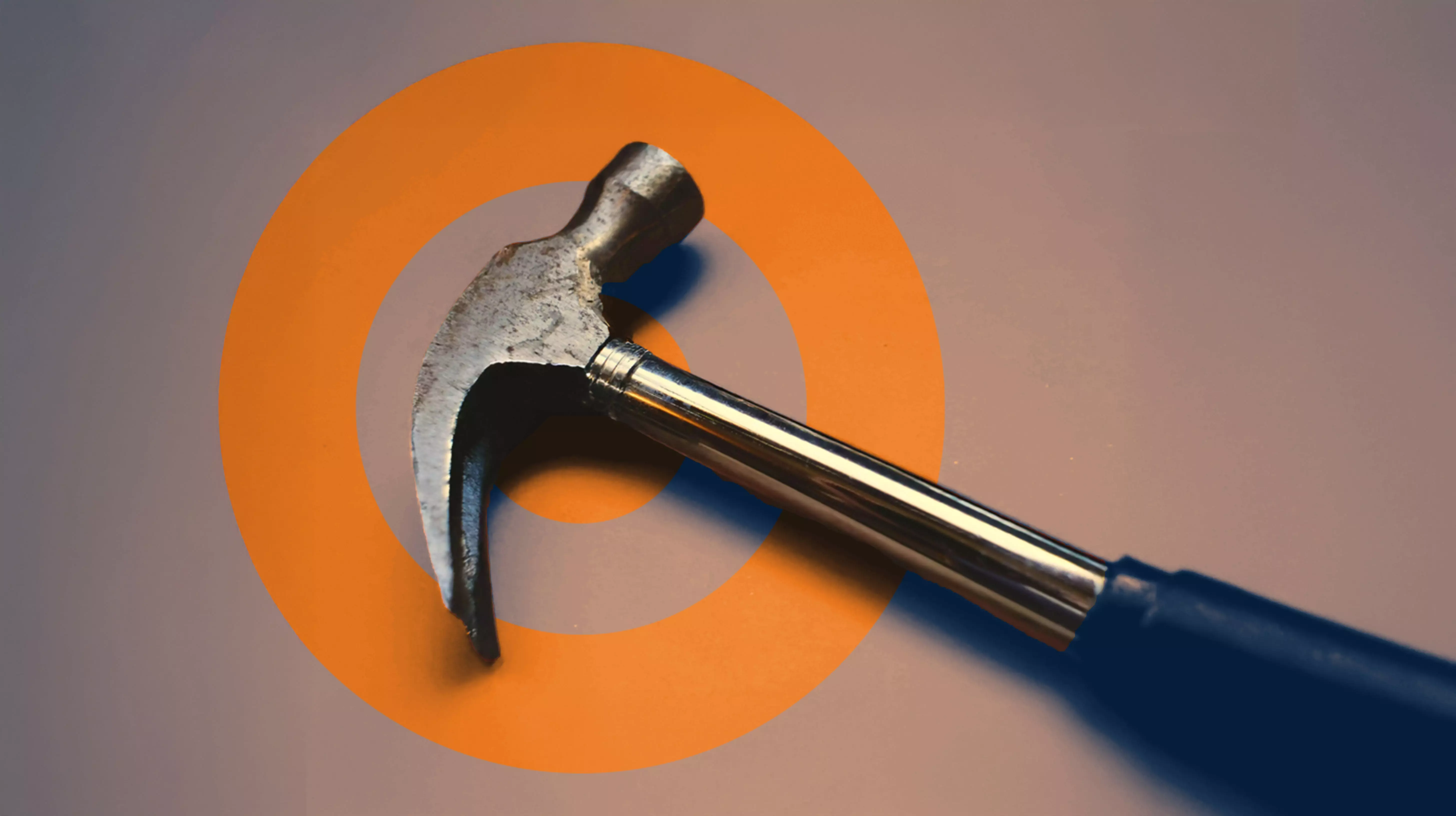 Close-up of a hammer placed on a flat surface with an ORANJEGROEP logo in the background.

